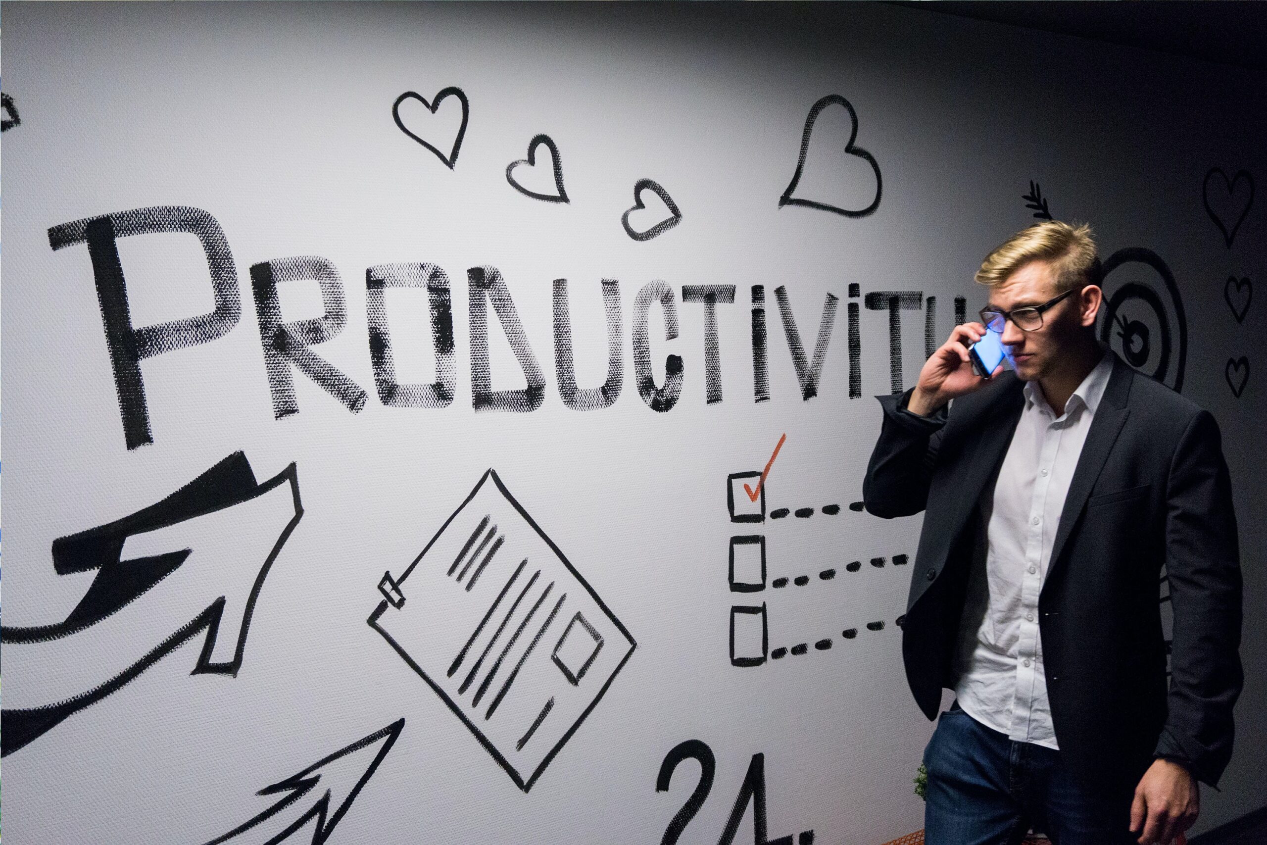 image of man on a cellphone walking in front of a whiteboard with the work "productivity" and other images to represent efficiency